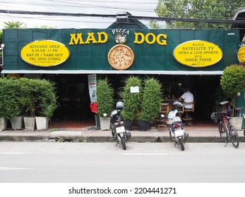 Chiang Mai, Thailand - 09,20,2022: Mad Dog  Restaurant And Bar With Customers Sitting Inside And Motorcycle Scooters Parked Outside.