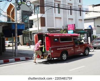 Chiang Mai, Thailand - 09,20,2022: Old Woman Climbing Into The Back Of A Red Taxi With Urban Background.