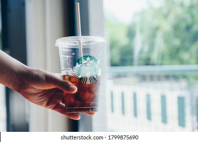 Chiang Mai, Thailand : 22/07/2020 : Someone holding a cup of Cold Brew coffee in Starbucks coffee shop. Cold brewing is a method of brewing that combines ground coffee and cool water.