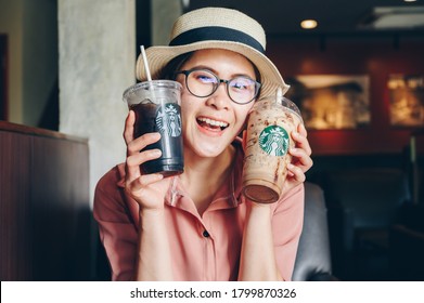 Chiang Mai, Thailand : 22/07/2020 : Tourist woman holding a cup of Choco-choco Nutty Frappuccino with Cold Brew coffee in Starbucks coffee shop.