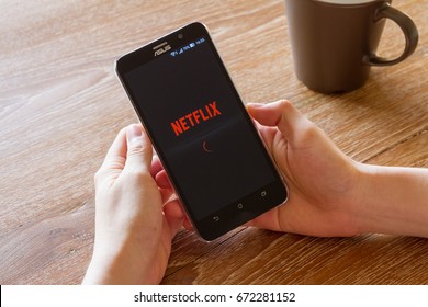 CHIANG MAI, THAILAND - APR 26, 2016: man hand holding screen shot of Netflix application showing on Asus Zenfone 2 mobile phone. Netflix is a global provider of streaming movies and TV series.