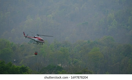 Chiang Mai, Thailand - April 8, 2020: Eurocopter AS350 Helicopter of Ministry of Natural Resources and Environment carries water to douse forest fires on Doi Suthep mountain