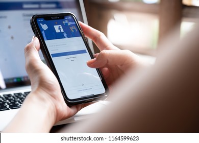 CHIANG MAI ,THAILAND - AUG 26, 2018 : Woman hand holding iPhone X to use facebook with new login screen.Facebook is a largest social network and most popular social networking site in the world.