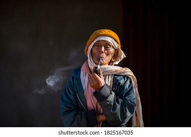 Chiang Mai / Thailand - Jan 16 2016 : Old Asian Man Carrying A Pipe And Smoking, Wearing Old Clothes And A Turban. Black Background, Hill Tribe Men In Rural Villages Of Northern Thailand.