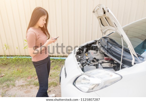 CHIANG MAI, THAILAND - July 1,2018:Woman and\
broken down car on street, Woman using mobile phone near a broken\
car, Auto Concept
