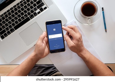 CHIANG MAI ,THAILAND - JULY 13, 2015: Young man touch Facebook icons on Apple iPhone 6 plus. Facebook is largest and most popular social networking site in the world.
