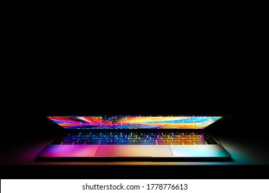 Chiang Mai, Thailand - July 18, 2020: Apple MacBook Retina Laptop Computer With Lid Half Open On A Table Lit With Colorful Desktop Screen Wallpaper In A Dark Room