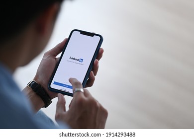CHIANG MAI,THAILAND - FEB 08, 2021 : Man holding I Phone 11 Pro max opening Linkedin app. Linkedin is social media website specialized in business networking. Illustrative editorial.