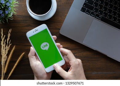 CHIANG MAI,THAILAND - January 20, 2019 : Man Holding Iphone 6  Alpha With Line App On The Screen On Wood Desk Office. Top View Of Business Workplace