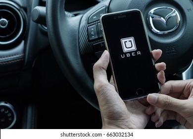 CHIANG MAI,THAILAND - JUNE 15, 2017 : A Uber Driver Hand Holding Uber App Showing On IPhone 6s On Road And Black Car, Uber Is Smartphone App-based Transportation Network.