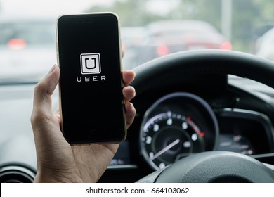 CHIANG MAI,THAILAND - JUNE 15, 2017 : A uber driver hand holding Uber app showing on iPhone 6s on road and black car, Uber is smartphone app-based transportation network.