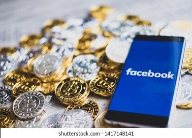 CHIANG MAI,THAILAND - JUNE 6,2019: fb coins new ico facebook app on smartphone screen and golden bitcoin coins on wooden floor.