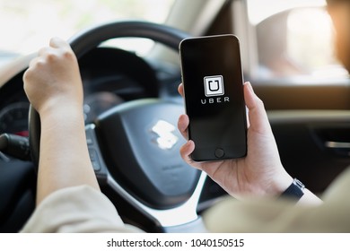 CHIANG MAI,THAILAND - MARCH 01, 2018 : A uber driver hand holding Uber app showing on iPhone 6s on road and black car, Uber is smartphone app-based transportation network.