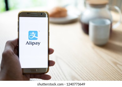 CHIANG MAI,THAILAND - Nov 14,2018: male hands holding smartphone using Alipay app on the screen at the coffee shop.