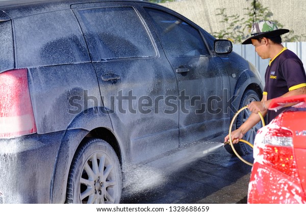 Chiang rai, Thailand - February 5,2019: Car\
wash,Men wearing black short-sleeved shirts and blue shorts are\
washing black cars.