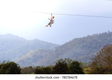 Chiang Rai, Thailand. November 24, 2017. Two Asian Tourists, Father And Son Wearing Casual Clothing Are Playing Zip Line And Selfie With Hill And Nature Background At Singha Park.