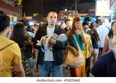 CHIANGMAI, THAILAND, 5 APRIL 2014 - A Man Is Bringing A Newborn Baby To The Public Place. Crowded People In The Night Market.