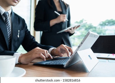 CHIANGMAI, THAILAND - DEC 07, 2019 : Microsoft Surface tablet on desk with businesman and businesswoman discussing background. created by Microsoft for Windows 10.