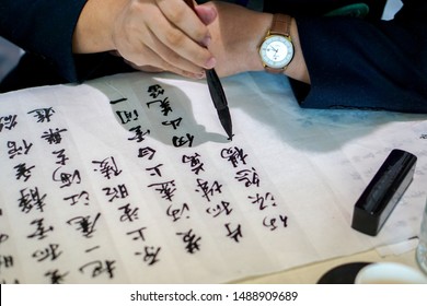 Chiangmai, Thailand, June 30 2019 : Closeup Hands Of Human Holding A Chinese Brush Learn And Writing Chinese Texts From Black Ink On A Paper In A Chinese Language Class.