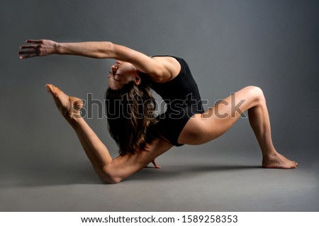 chiaroscuro theatrically light, oriental exterior slim girl shows yoga poses on dark background