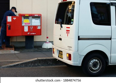 CHIBA, JAPAN - December 31, 2020: Post Office Van By A Post Box In Chiba Prefecture With A Mail Carrier Emptying It In The Background During The New Year Period. Selective Focus, Focus On Foreground.