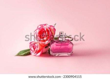 A chic bottle of perfume or eau de parfum with notes of delicate roses on a pink background with rosebuds. front view. aroma presentation.