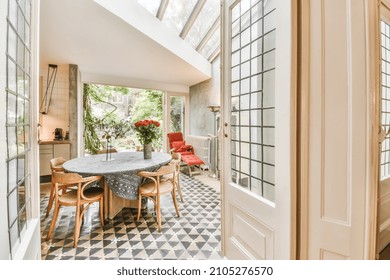 Chic dining room with round table with tablecloth and wooden chairs and black and white floor