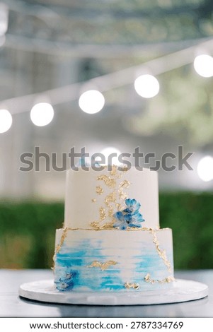 Chic evening garden setting showcasing delicately decorated twotier cake with embellishments