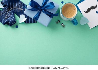 Chic Father's Day arrangement. Overhead shot of postcard, ribbon-tied giftbox, necktie, cufflinks, spectacles, paper hearts, coffee mug on teal backdrop with space for text