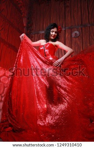 chic girl with black hair decorated by red rose pink as a pin up Gypsy woman in a lacquer corset and a big sparkle skirt alone