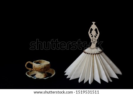 Chic glamorous clay tea pair decorated with glaze and elegant stylized stand for napkins on black background. Minimal style. Concept - serving, decor, tea, restaurant, cafe.