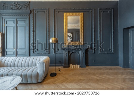 chic interior of the room in the Renaissance style of the 19th century with modern luxury furniture. walls of noble dark color are decorated with stucco and gilded frames, wooden parquet.