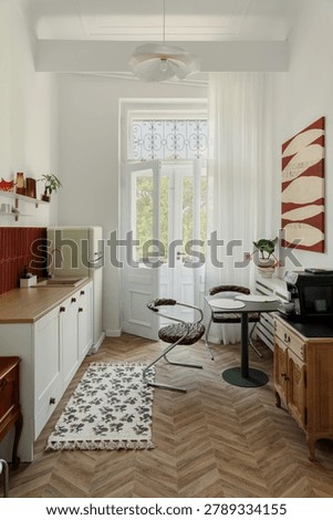 A chic, minimalist kitchen with a warm, inviting atmosphere, featuring sleek appliances, wooden floors, an open door, and bright natural light