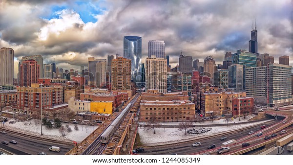 Chicago cityscape from the West Loop neighborhood\
with an eastward perspective. A cloudy winter afternoon at Lake\
Street and Interstate 90. Panorama, urban skyline with snow on the\
ground.