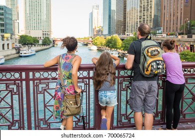 Chicago, IL, August 18, 2017: A Young Family Looks Out Over The Chicago River And Lake Michigan, Standing On One Of The Iconic Red Bridges Downtown. Chicago Attracts Millions Of Tourists Each Year.