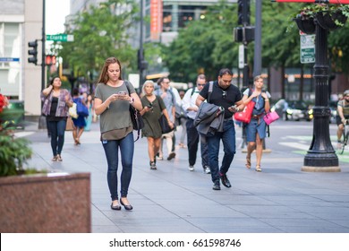 CHICAGO, IL, June 15, 2017: Young Woman Checks Her Phone While Walking, Downtown Chicago. Cell Phones Are Ubiquitous In The City, And Many People Text And Check Social Media While Walking Or Commuting