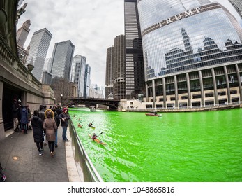 Chicago, IL - March 17th 2018: People Walk Along The Freshly Green Dyed Chicago River On Saturday As Kayak Boats Pass By During The City's Annual St. Patrick's Day Celebration On Saturday.