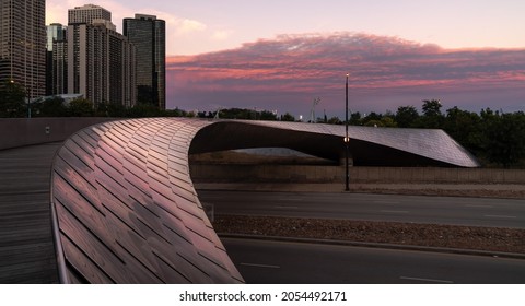 Chicago, IL - September 23rd, 2021: A colorful sunset sky reflects pink and blue clouds on the BP pedestrian serpentine footbridge over Columbus Drive connecting Millennium Park to Maggie Daley Park.