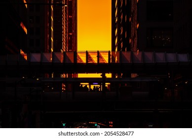 Chicago, IL - September 23rd, 2021: A CTA Train Passes Through The Washington And Wabash Stop Carrying Passengers As The Sun Sets Between The Buildings During The Semi Annual Henge Phenomenon.