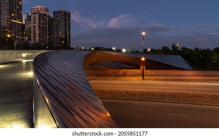 Chicago, IL - September 23rd, 2021: The city lights turn on as night sets in near the BP pedestrian serpentine footbridge over Columbus Drive connecting Millennium Park with Maggie Daley Park.