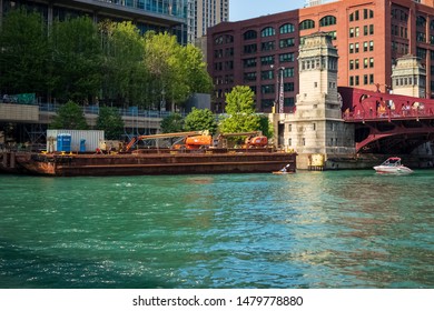 Chicago, IL / USA - 7/25/19: Construction Barge Floats Next To Skyscraper In Contrasting Size To Kayak & Motorboat On Chicago River Near LaSalle Street