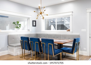 CHICAGO, IL, USA - APRIL 1, 2021:  A Modern, Corner Dining Room With Bench Seating, A Gold Sputnik Chandelier, Blue Chairs With Gold Legs Surrounding A Wooden Table, And Hardwood Floors.