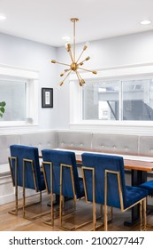 CHICAGO, IL, USA - APRIL 1, 2021:  A Modern, Corner Dining Room With Bench Seating, A Gold Sputnik Chandelier, Blue Chairs With Gold Legs Surrounding A Wooden Table, And Hardwood Floors.