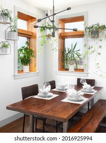 CHICAGO, IL, USA - APRIL 2, 2021: A Bohemian Style Dining Room With A Wooden Table And Seating, A Modern Sputnik Chandelier, And Table Setting For Four People.