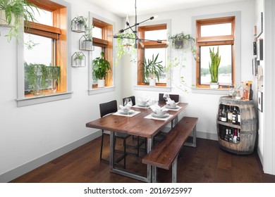 CHICAGO, IL, USA - APRIL 2, 2021: A Bohemian Style Dining Room With A Wooden Table And Seating, A Modern Sputnik Chandelier, And Table Setting For Four People.