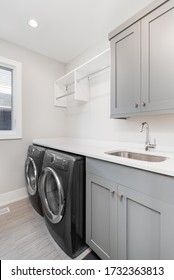 CHICAGO, IL, USA - APRIL 23, 2020: A Renovated Laundry Room With Grey Cabinets, White Granite, A Stainless Steel Faucet, And New Electrolux Washer And Dryer.