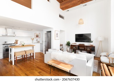 CHICAGO, IL, USA - APRIL 5, 2021: A stylish, bohemian styled loft with cozy furniture, high ceilings, and a white kitchen with an island and stainless steel appliances.