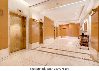 CHICAGO, IL, USA - AUGUST 16, 2019: A Elevator Lobby At An Expensive Chicago High Rise With Gold Elevator Doors And Tiles Covering The Hallway Floor.