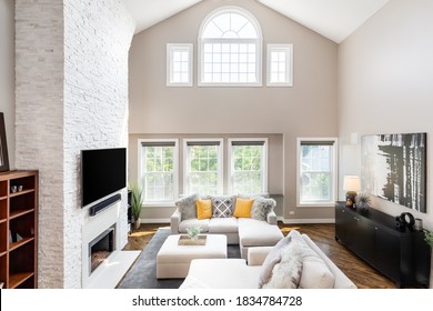 CHICAGO, IL, USA - AUGUST 19, 2019: A Large Living Room With High Ceilings, Oversized Seating, Yellow Accents, And A Stone Fireplace.