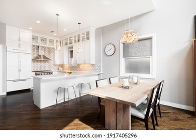 CHICAGO, IL, USA - AUGUST 19, 2019: Looking from the dining room to the kitchen with white cabinets and stainless steel appliances. Lights hanging above the dining room and kitchen counter island.